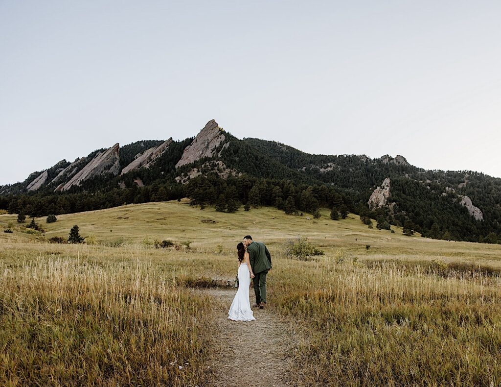 Bride and Groom walk towards mountains and kiss after their Colorado Elopement Wedding Ceremony.