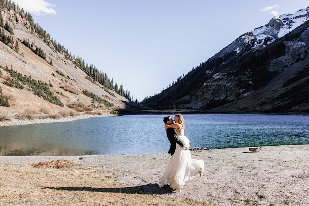 Groom lifts up the bride near a cove in the Colorado Mountains during their intimate elopement. 
