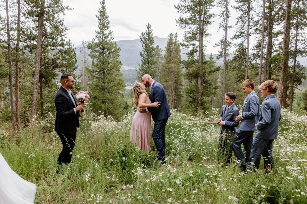 Bride and Groom surrounded by their children kiss during an intimate wedding ceremony in the mountains of Breckenridge, Colorado. 