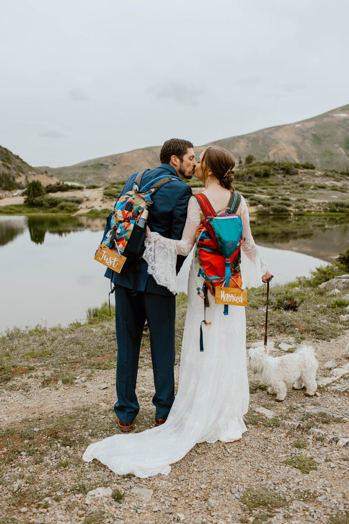 Bride and Groom kiss and pose with hiking backpacks while hiking through the mountains in Breckenridge Colorado for their wedding elopement. 