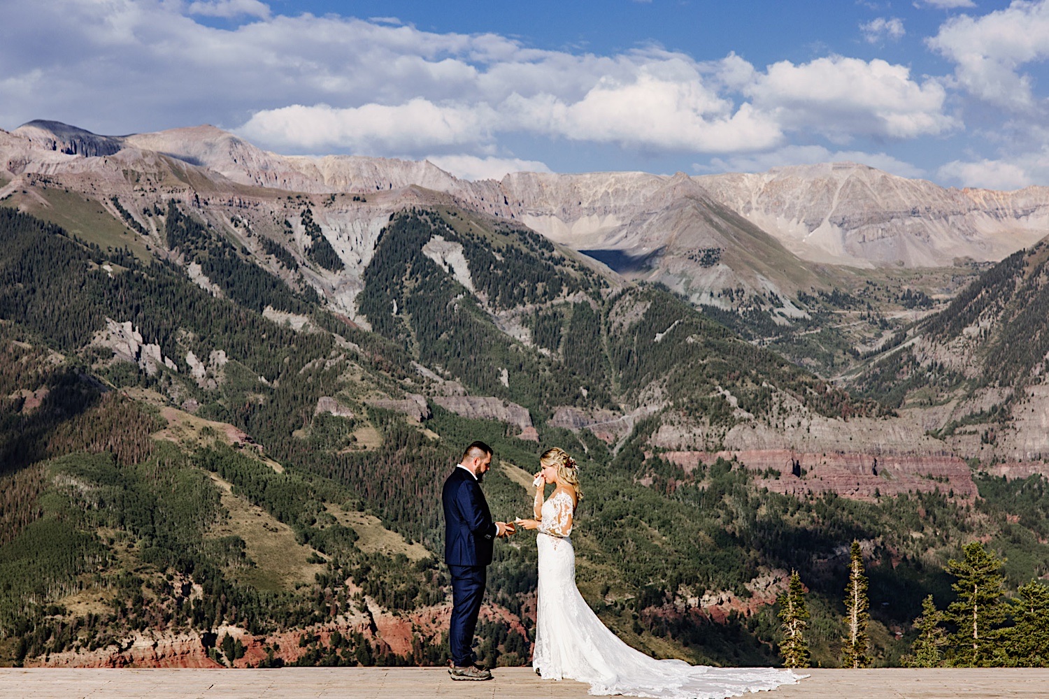Bride wipes away her tears as Groom reads his vows during intimate wedding elopement on a mountain in Colorado.