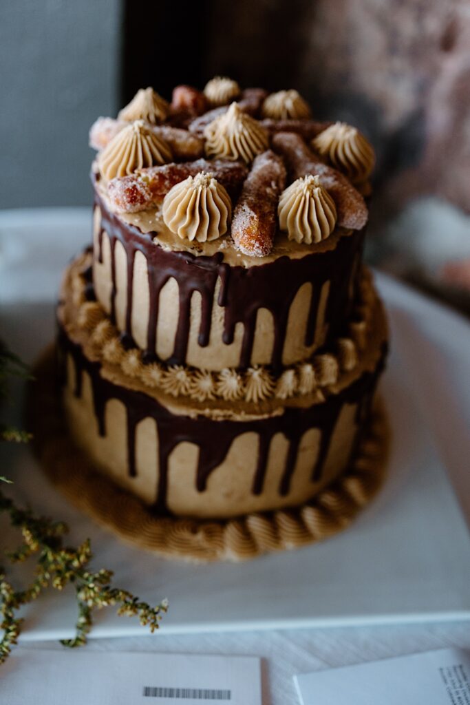 Double tiered chocolate dripped cake sits at reception table.